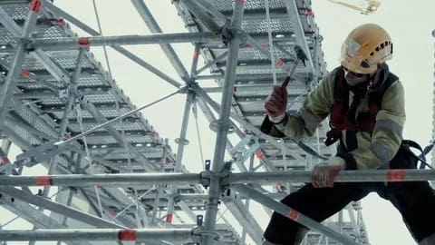 Scaffolding worker securing steel scaffolding structure with safety harness