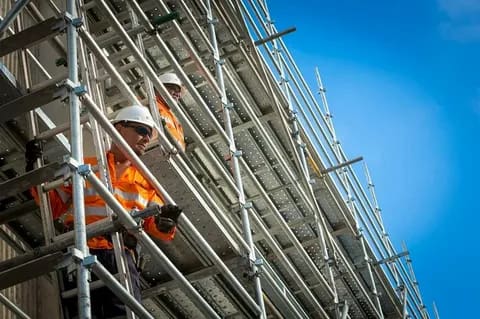 Construction workers working on metal scaffolding at a building site
