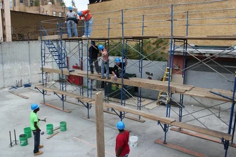 Scaffolding workers installing steel scaffolding at a Brooklyn NYC construction site