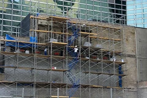 Workers on multi-level scaffolding repairing a building exterior.