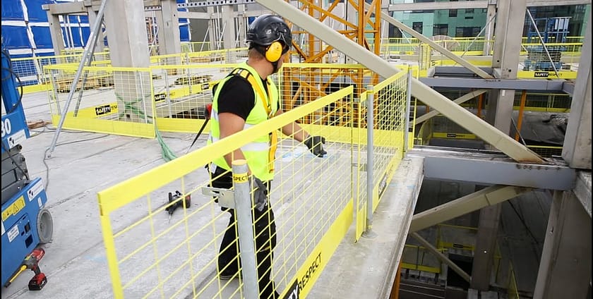 Worker using safety barriers on elevated construction site